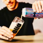 rapaz a segurar lata de cerveja artesanal espanha Oso brew Co Aura Neipa 44 cl e a servir um copo que já está quase cheio