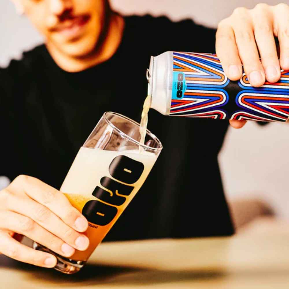 rapaz a segurar lata de cerveja artesanal espanha Oso brew Co Aura Neipa 44 cl e a servir um copo que já está quase cheio
